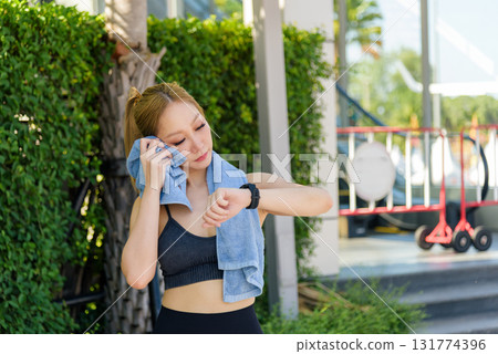 Sport woman outdoor workout, fit people stretch during exercise break, wiping sweat with towel, checking watch, preparing body to stretch for full recovery. Sport woman outdoor workout, fit people stretch during exercise break, wiping sweat with towel, checking watch, preparing body to stretch for full recovery. 131774396
