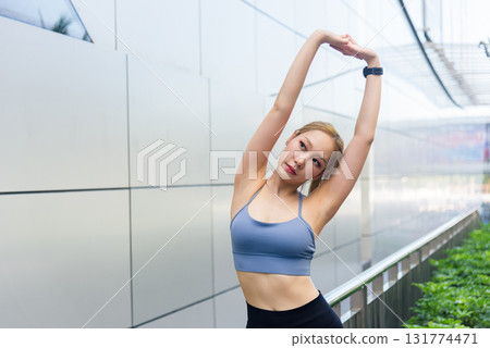 Fit woman performs sport exercise workout outdoor, stretching for flexibility, maintaining fit physique, promoting healthy lifestyle, inspiring urban active people. 131774471