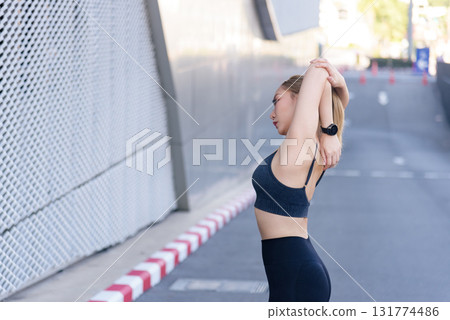 Sport woman performs exercise workout, stretching arms outdoor for fitness, fit physique, preparing for active sport session, enjoying urban environment for healthy lifestyle, maintaining wellbeing. Sport woman performs exercise workout, stretching arms outdoor for fitness, fit physique, preparing for active sport session, enjoying urban environment for healthy lifestyle, maintaining wellbeing. 131774486