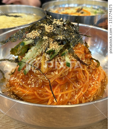 Cold and refreshing Korean naengmyeon noodles, served in a chilled broth with sliced cucumber, radish, and a boiled egg. A savory, tangy dish ideal for hot summer days. 131774875