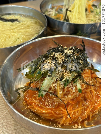 Cold and refreshing Korean naengmyeon noodles, served in a chilled broth with sliced cucumber, radish, and a boiled egg. A savory, tangy dish ideal for hot summer days. 131774876