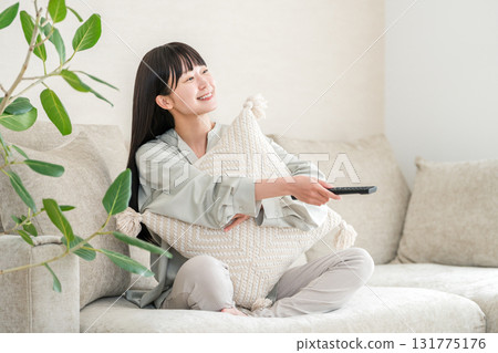 坐在客廳沙發上看電視的年輕亞洲女人 131775176
