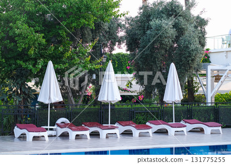 A row of white umbrellas are set up in front of a pool 131775255