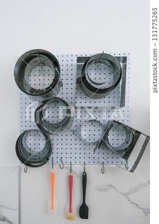 A collection of baking tools are hanging on a pegboard 131775265