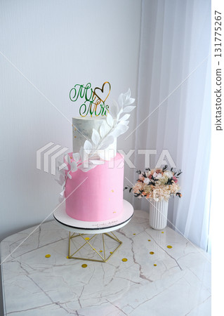 A pink and white wedding cake with a green leaf on top and the words "Mr A pink and white wedding cake with a green leaf on top and the words "Mr 131775267