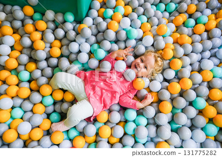 Girl playing in the pool with colored balloons in the children's center 131775282