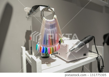 A nail polish color chart hangs on a white shelf next to a nail polish remover 131775305