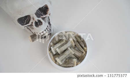 Skull Chewing Tobacco on a White Table. 131775377