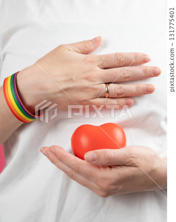 Woman with engagement ring and rainbow bracelet holding heart.  Woman with engagement ring and rainbow bracelet holding heart.  131775401