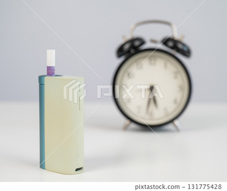 Electronic cigarette and alarm clock on white background. Tobacco heating systems. 131775428