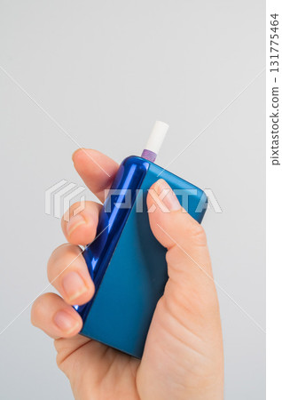 Woman holding electronic cigarette on white background. Tobacco heating systems. Woman holding electronic cigarette on white background. Tobacco heating systems. 131775464