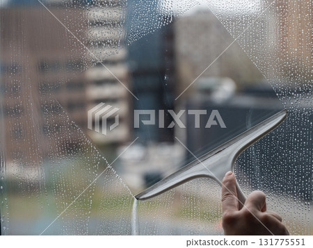 A woman washes a window with a special scraper.  131775551