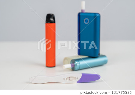 Pregnancy test and electronic cigarette and disposable vape on white table. Pregnancy test and electronic cigarette and disposable vape on white table. 131775585