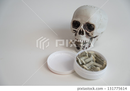 Skull Chewing Tobacco on a White Table. 131775614