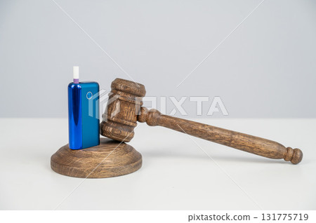 Judge's gavel hits e-cigarette. Smoking ban. Tobacco heating systems.  131775719