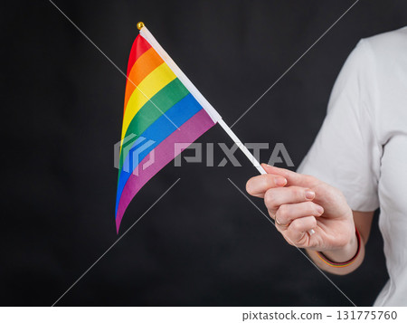 Woman with wedding ring holding rainbow flag on black background. Woman with wedding ring holding rainbow flag on black background. 131775760