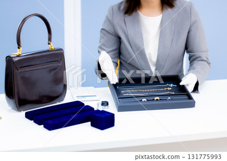 A woman's hands assessing items at a purchasing company counter 131775993
