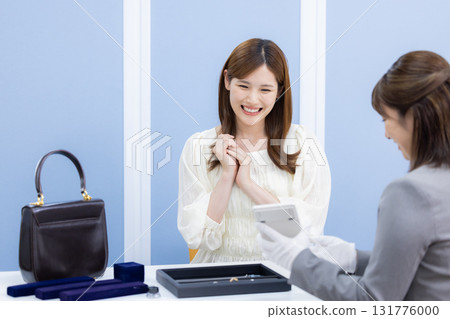 A woman having her bag and precious metals appraised by a buyer A woman having her bag and precious metals appraised by a buyer 131776000