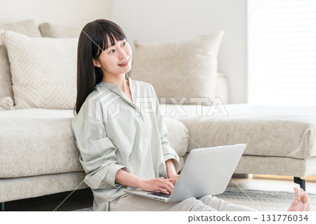 A woman using a computer on the sofa in the living room (video, side job, SNS, work from home) 131776034