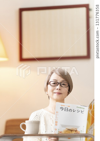 一位老年婦女在客廳看食譜書 一位老年婦女在客廳看食譜書 131776358