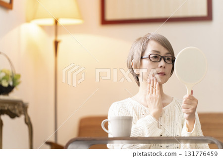 一位老年婦女在客廳看著手鏡 一位老年婦女在客廳看著手鏡 131776459