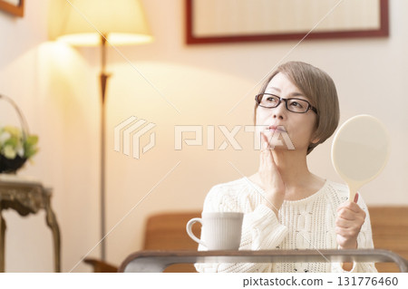 一位老年婦女在客廳看著手鏡 一位老年婦女在客廳看著手鏡 131776460
