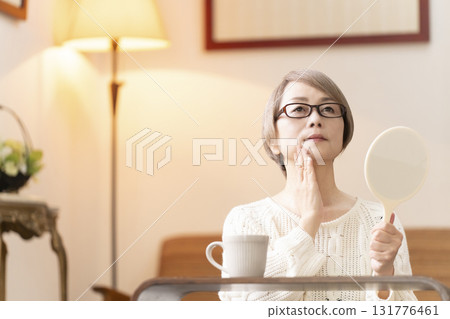 一位老年婦女在客廳看著手鏡 一位老年婦女在客廳看著手鏡 131776461