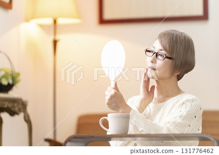 一位老年婦女在客廳看著手鏡 一位老年婦女在客廳看著手鏡 131776462