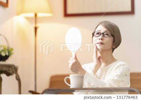 一位老年婦女在客廳看著手鏡 一位老年婦女在客廳看著手鏡 131776463