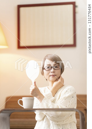 一位老年婦女在客廳看著手鏡 131776484