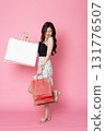 Young Asian Woman looking at camera while holding shopping bags on pink background 131776507