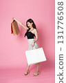 Young Asian Woman looking at camera while holding shopping bags on pink background 131776508
