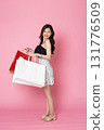 Young Asian Woman looking at camera while holding shopping bags on pink background 131776509