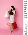 Young Asian Woman looking at camera while holding shopping bags on pink background 131776511