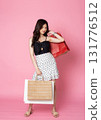Young Asian Woman looking at camera while holding shopping bags on pink background 131776512