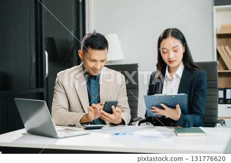 Two business workers talking on the smartphone and using laptop at the office. Two business workers talking on the smartphone and using laptop at the office. 131776620