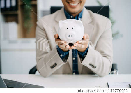 Men are putting coins in a piggy bank for a business that grows for profit and saving money for the future. 131776951