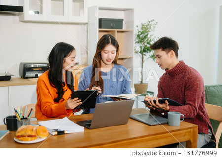 Teamwork and creativity with young adults collaborating on laptops and tablets in a cozy workspace. 131776999