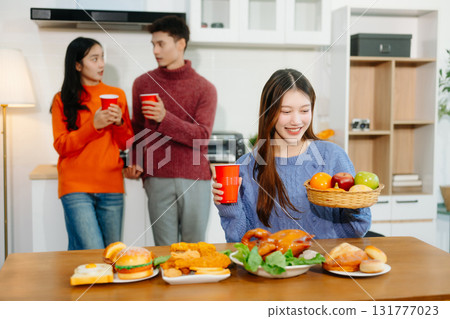 Young Asian friends enjoy a cozy dinner party at home, sharing food, drinks, and laughter in a warm modern kitchen. Young Asian friends enjoy a cozy dinner party at home, sharing food, drinks, and laughter in a warm modern kitchen. 131777023