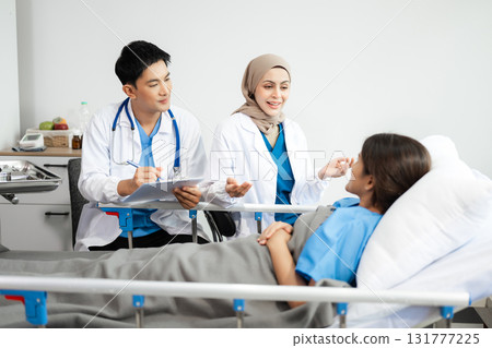 Hospital Ward Male and Male Professional Asian Doctors Talk with a Patient, Give Health Care Advice, Recommend Treatment Plan Hospital Ward Male and Male Professional Asian Doctors Talk with a Patient, Give Health Care Advice, Recommend Treatment Plan 131777225