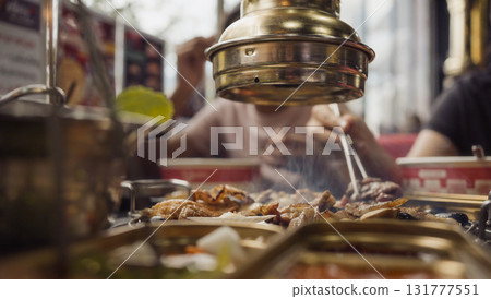 Hand cooking smoked grilled pork on iron grill pan in Korean BBQ in restaurant. Traditional Korea style food barbecue pork belly steak on charcoal grill. 131777551