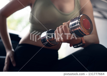 Young asian woman doing exercise and lifting dumbbells weights at sport gym. 131777664
