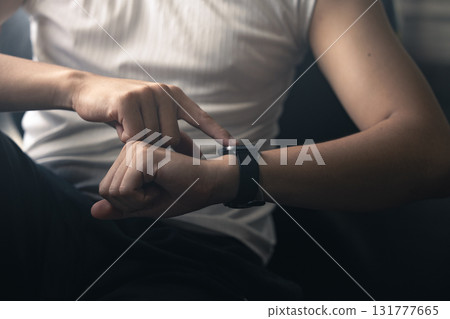 Young Asian man in sportswear checking her workout results on a smart watch while resting at the gym. 131777665