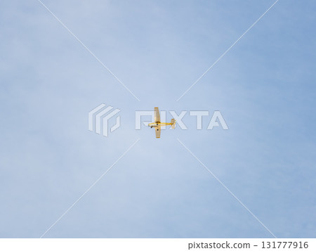 Small ultralight airplane with overhead wing and single propeller flying in sunset sky. 131777916