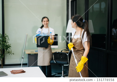 Two professional cleaners tidying a stylish space with a smile. Experience efficient and friendly house cleaning 131778558