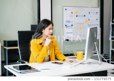 Young Asian businesswoman working with working notepad, tablet and laptop documents talking Young Asian businesswoman working with working notepad, tablet and laptop documents talking 131778575