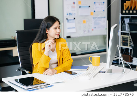 Young Asian businesswoman working with working notepad, tablet and laptop documents talking 131778576