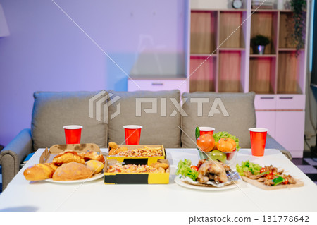 Mouth watering pizza, roasted chicken, fresh fruits, and drinks on a table. Perfect for food celebrations, gatherings, 131778642