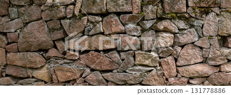 Rustic stone wall with moss in natural outdoor setting - texture and background 131778886