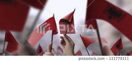 Albania flags in their hands on a blurred urban background 131779311